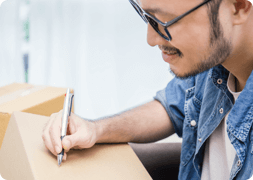 Man writing on large parcel ready to ship