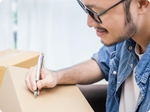 Man writing on large parcel ready to ship